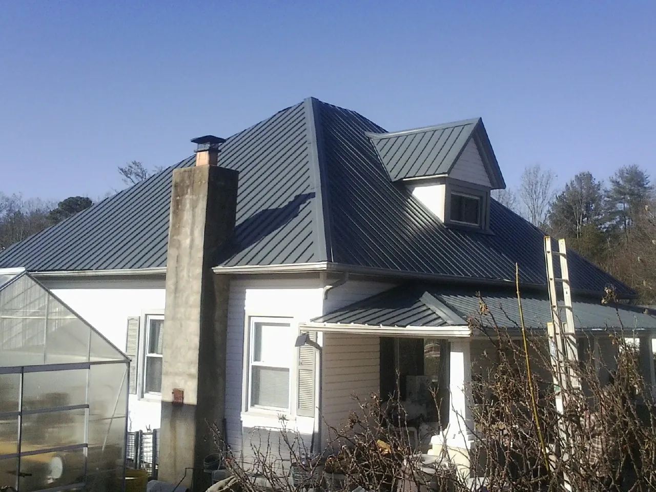 Dark blue standing seam metal roof on a white farmhouse with dormer — Slate & Tile Roof Repair by Roofing Brothers in Inverness