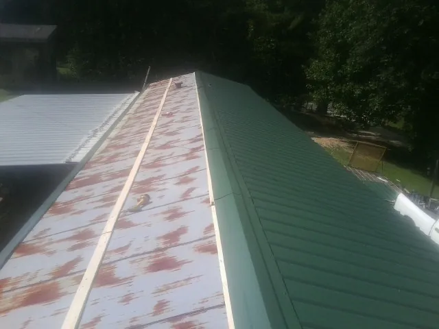 Old rusted panels beside newly installed green metal roofing — Wind Damage Roof Repair by Roofing Brothers in Inverness
