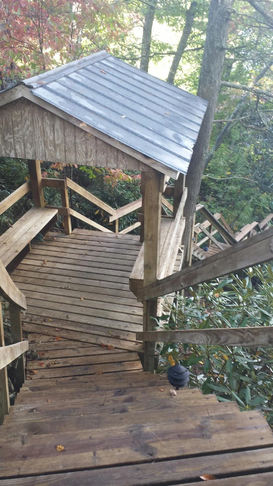 Metal roofed shelter over wooden steps on a wooded walkway — Skylight Repair & Installation work by our crew in Inverness