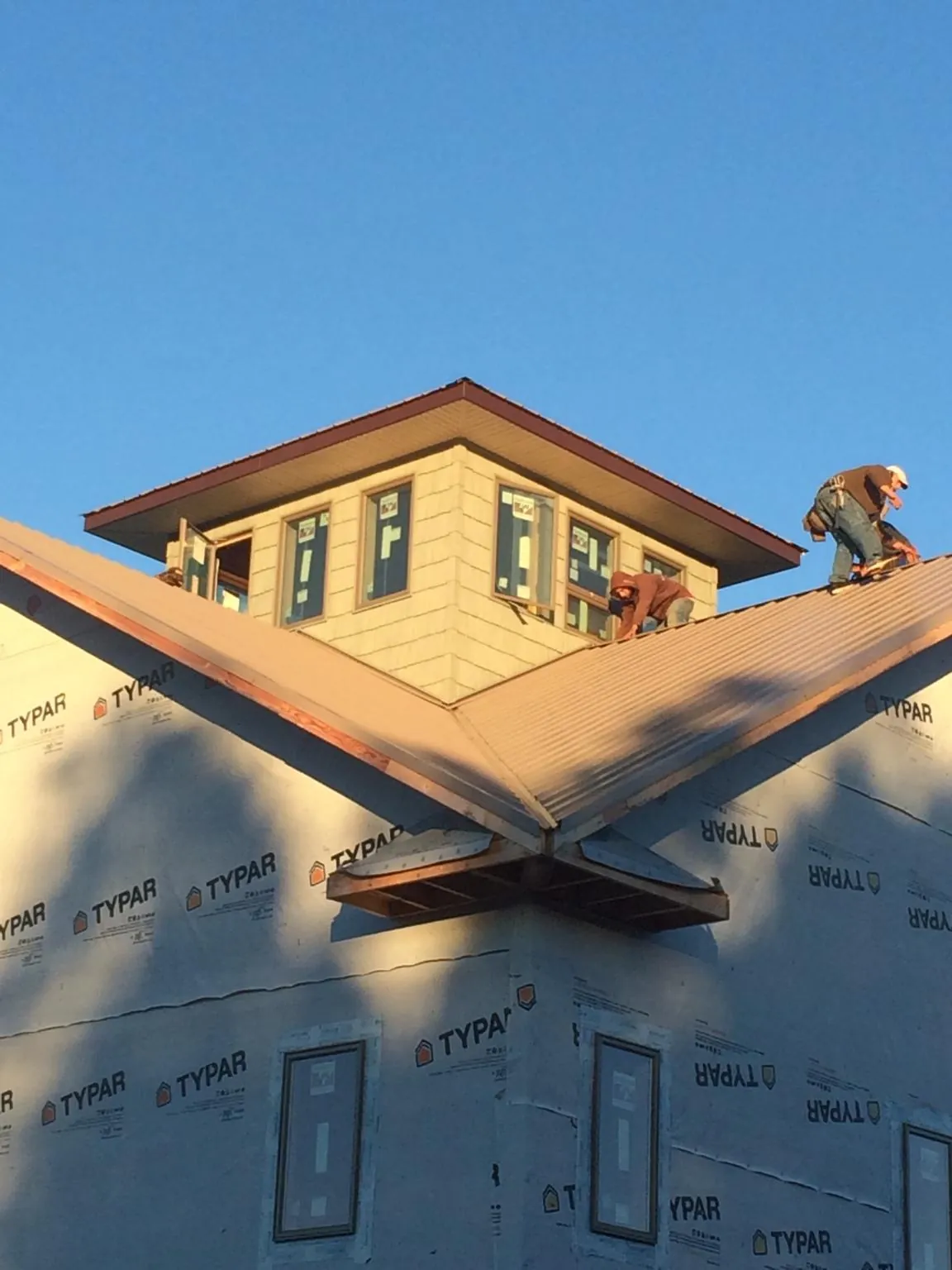 Roofers working around a rooftop cupola on a new metal roof at sunset — Roof Waterproofing in Inverness by Roofing Brothers
